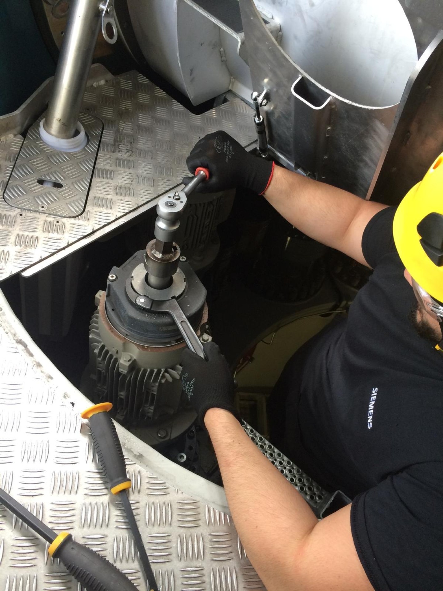 Dominic Connolly, WTS Founding Director, kneeling inside a wind turbine nacelle using a torque wrench on a motor during his time as a Siemens technician.